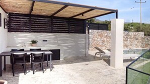 An outdoor patio with a dining area, a pool, and a stone wall. - Holiday home in Plakias with swimming pool (Plakias)