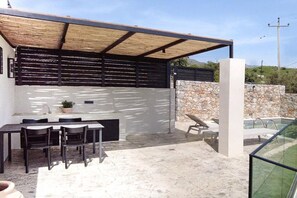 An outdoor patio with a dining area, a pool, and a stone wall. - Holiday home in Plakias with swimming pool (Plakias)
