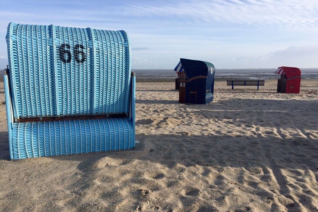 Una playa con una silla azul marcada con el número 66, una estructura azul con el número 82 y una estructura roja.