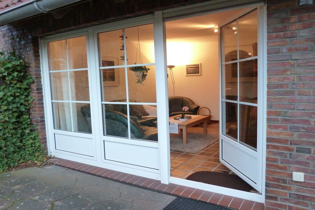 Une pièce dotée d’une grande porte-fenêtre coulissante, d’un canapé, d’une petite table sur laquelle se trouve un vase, et d’une lampe.