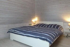 Ein Schlafzimmer mit einem Bett, zwei Nachttischlampen und einer Holzwand.