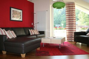 Ein modernes Wohnzimmer mit einem schwarzen Ledersofa, einem Glastisch und einem roten Teppich.