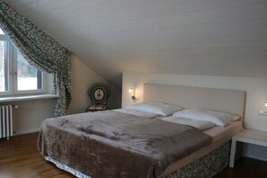 A bedroom with a bed, a nightstand, a wall clock, and a window with curtains. - House Seewiese No. 3 (Titisee-Neustadt)