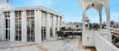 A rooftop terrace with a white gazebo, a dining area with chairs and a table, and a view of the cityscape.