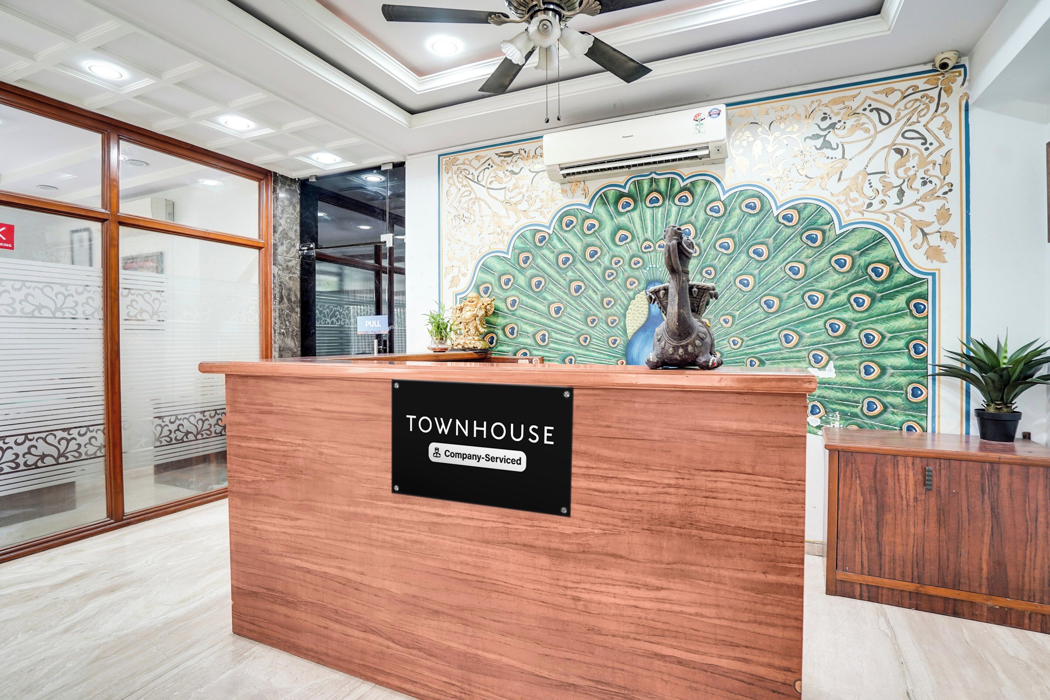 A reception desk with a 'Townhouse' sign, a ceiling fan, and a decorative peacock mural.