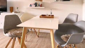 Ein stilvoller Essbereich mit einem weißen Tisch, grauen Stühlen und Holzboden.