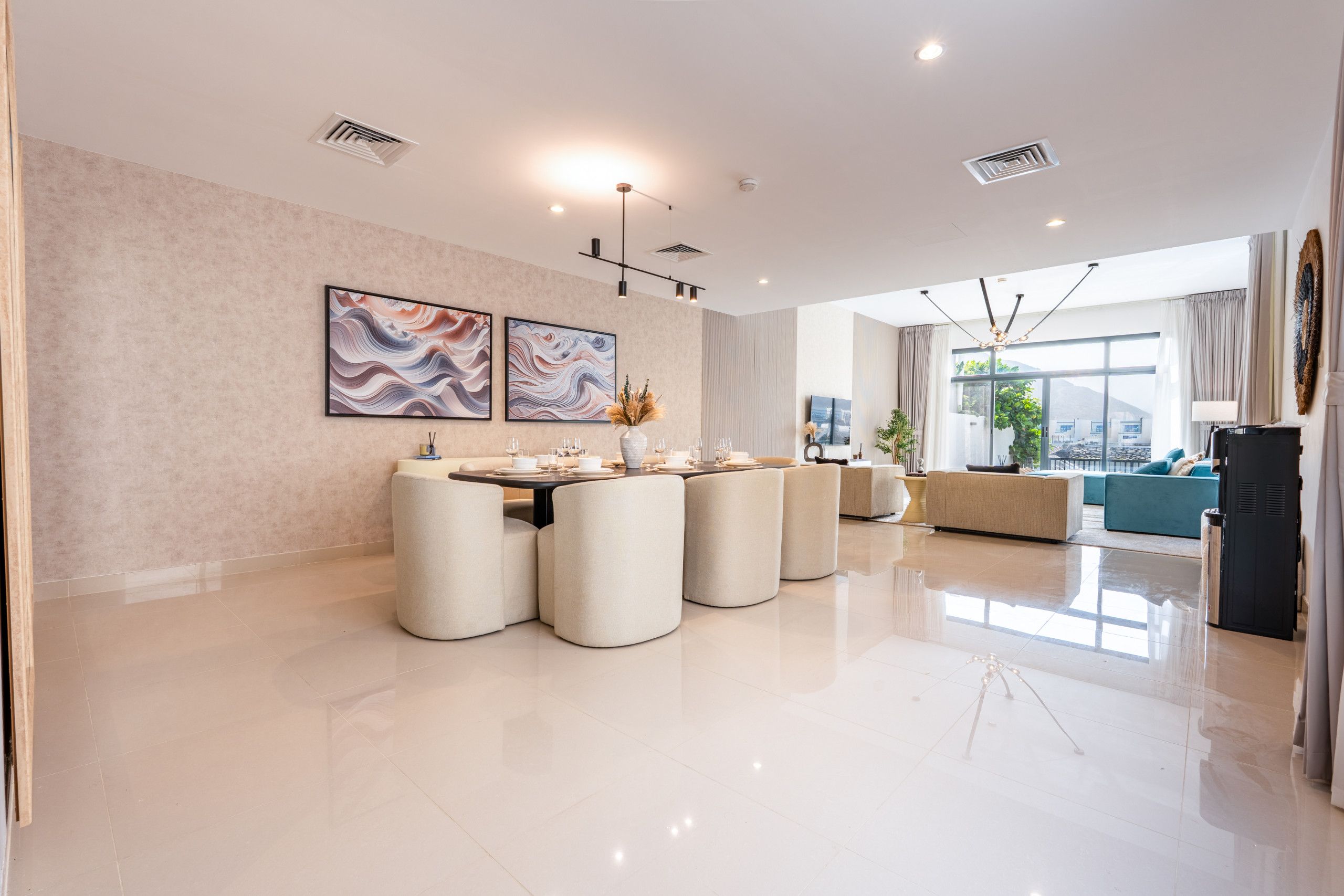 A modern dining area with a round table, cushioned chairs, and artwork on the wall.