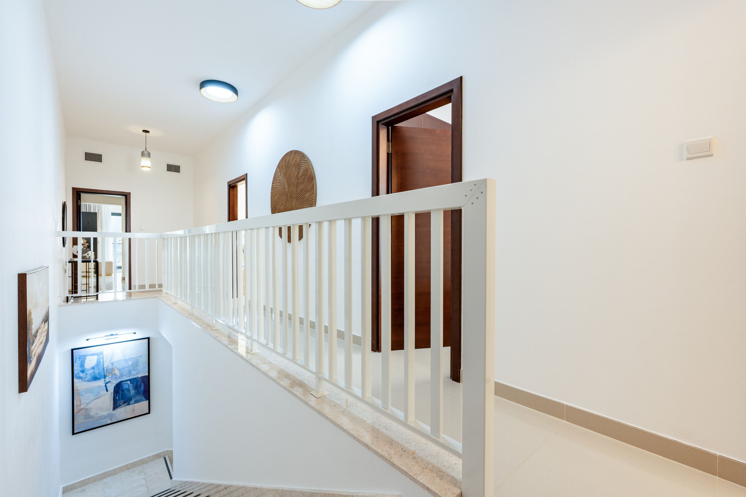 A modern interior with a white staircase, wooden doors, and a white railing.