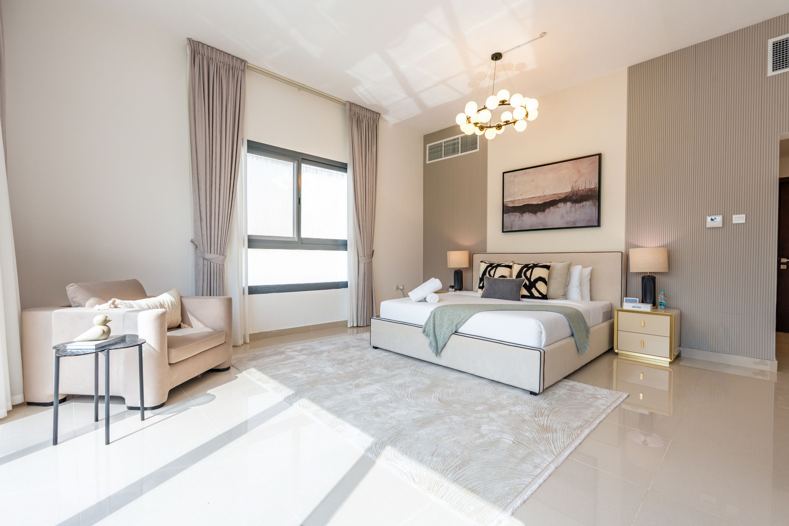A modern bedroom with a large bed, a seating area with a sofa, and a small table.