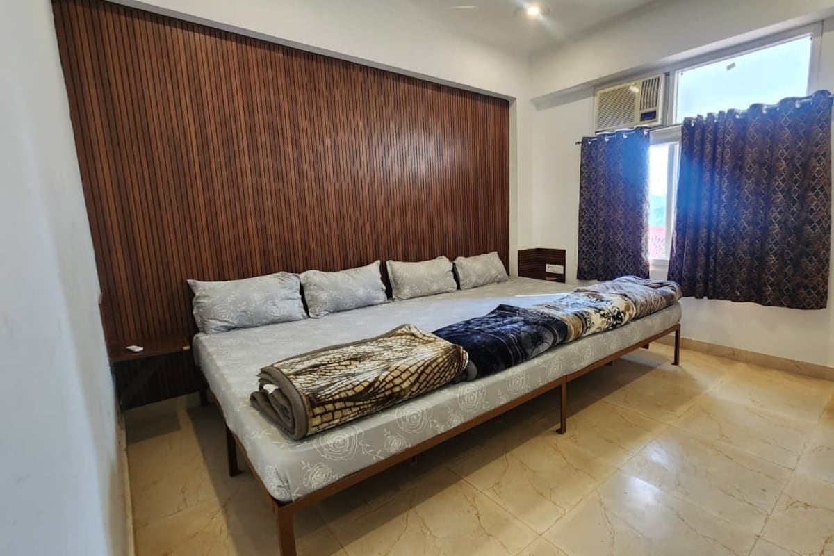 Un dormitorio con cama, cabecero de madera, ventana con cortinas y piso de baldosas.