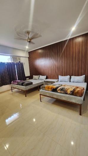 Habitación de hotel con cama, sofá, ventilador de techo y panel de pared de madera.