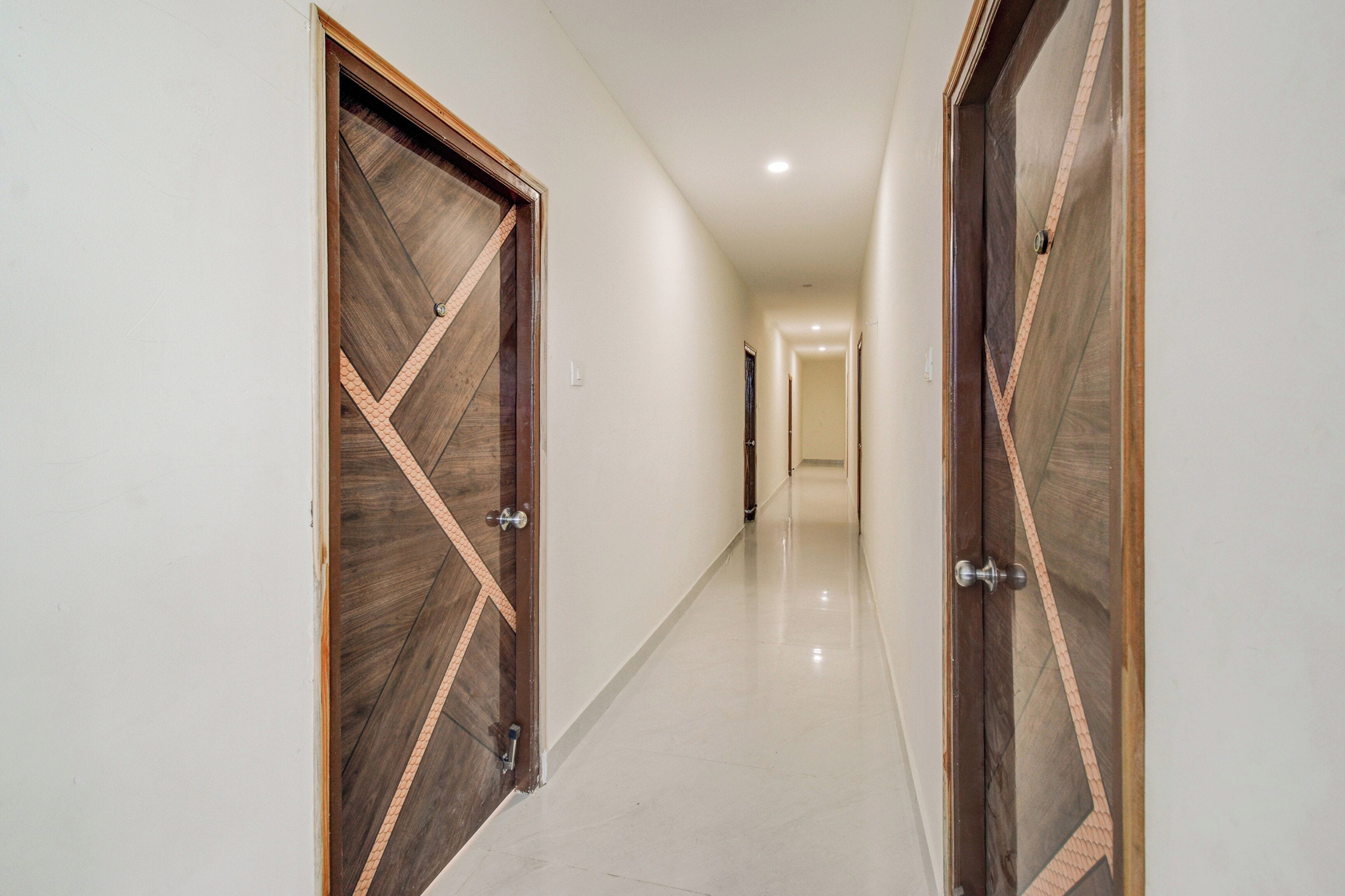 A hallway with two wooden doors featuring geometric patterns, leading to a room.