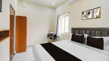 Una habitación de hotel con una cama, un escritorio, una silla y una ventana con cortinas.