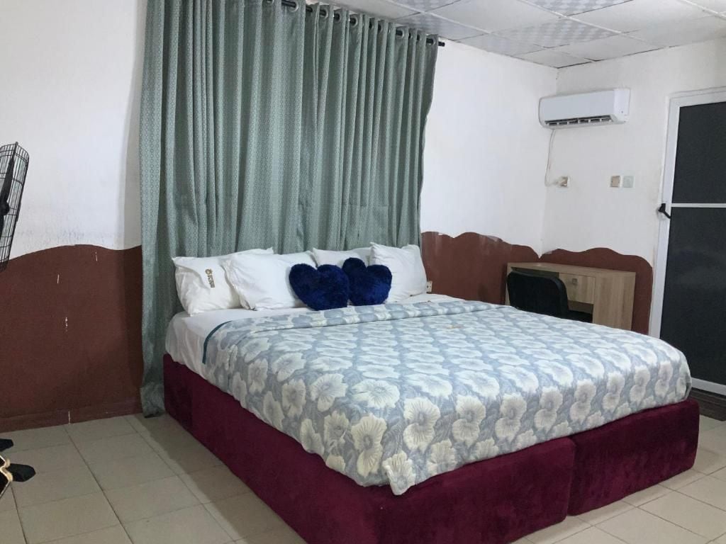 A bedroom with a bed, curtains, an air conditioning unit, and a door.