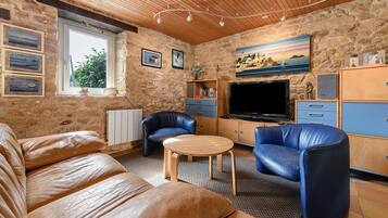 Un salon chaleureux avec des canapés en cuir, une table basse en bois et un téléviseur.