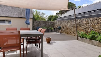 An outdoor patio area with a table and chairs, a covered seating area, and a stone wall.