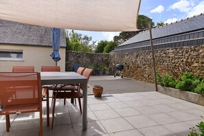An outdoor patio area with a table and chairs, a covered seating area, and a stone wall.