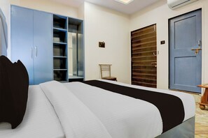 Een slaapkamer met een bed, een kledingkast, een deur en een klein tafeltje.