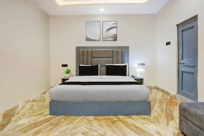 Een moderne slaapkamer met een groot bed, een hoofdbord, nachtkastjes, een deur en twee kunstwerken aan de muur.