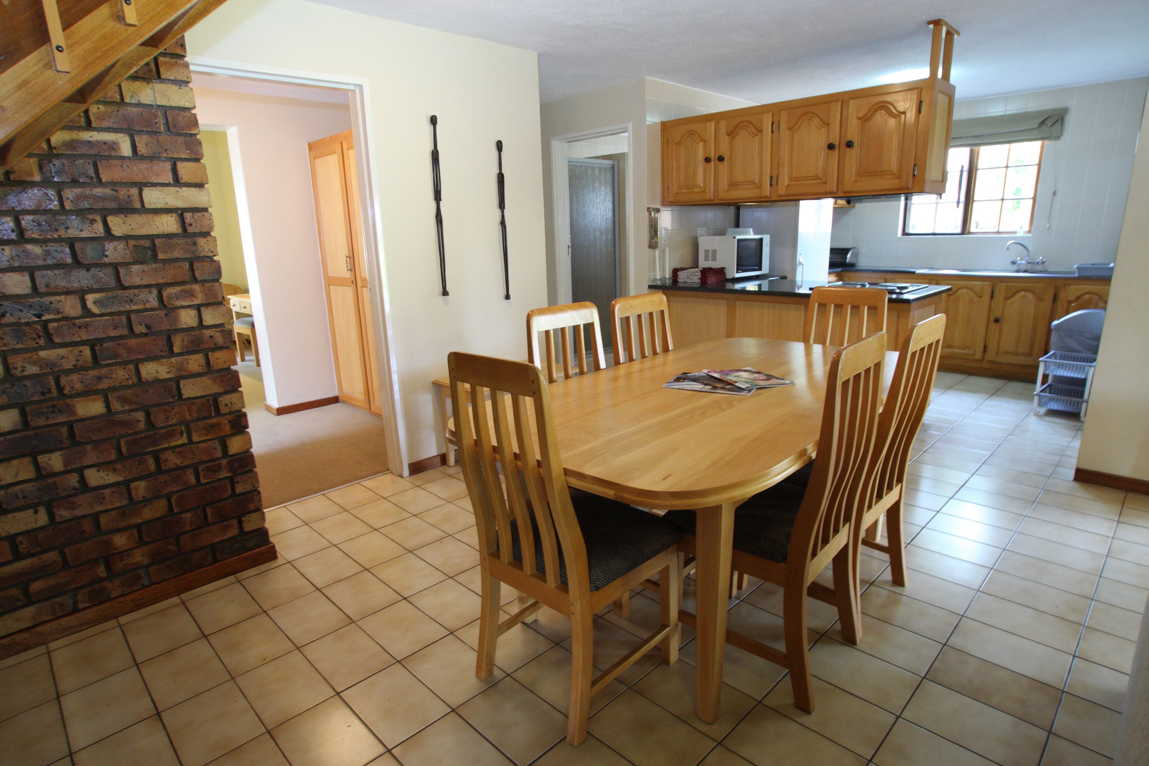 Un comedor con mesa y sillas de madera, una cocina con armarios de madera y una pared de ladrillo.