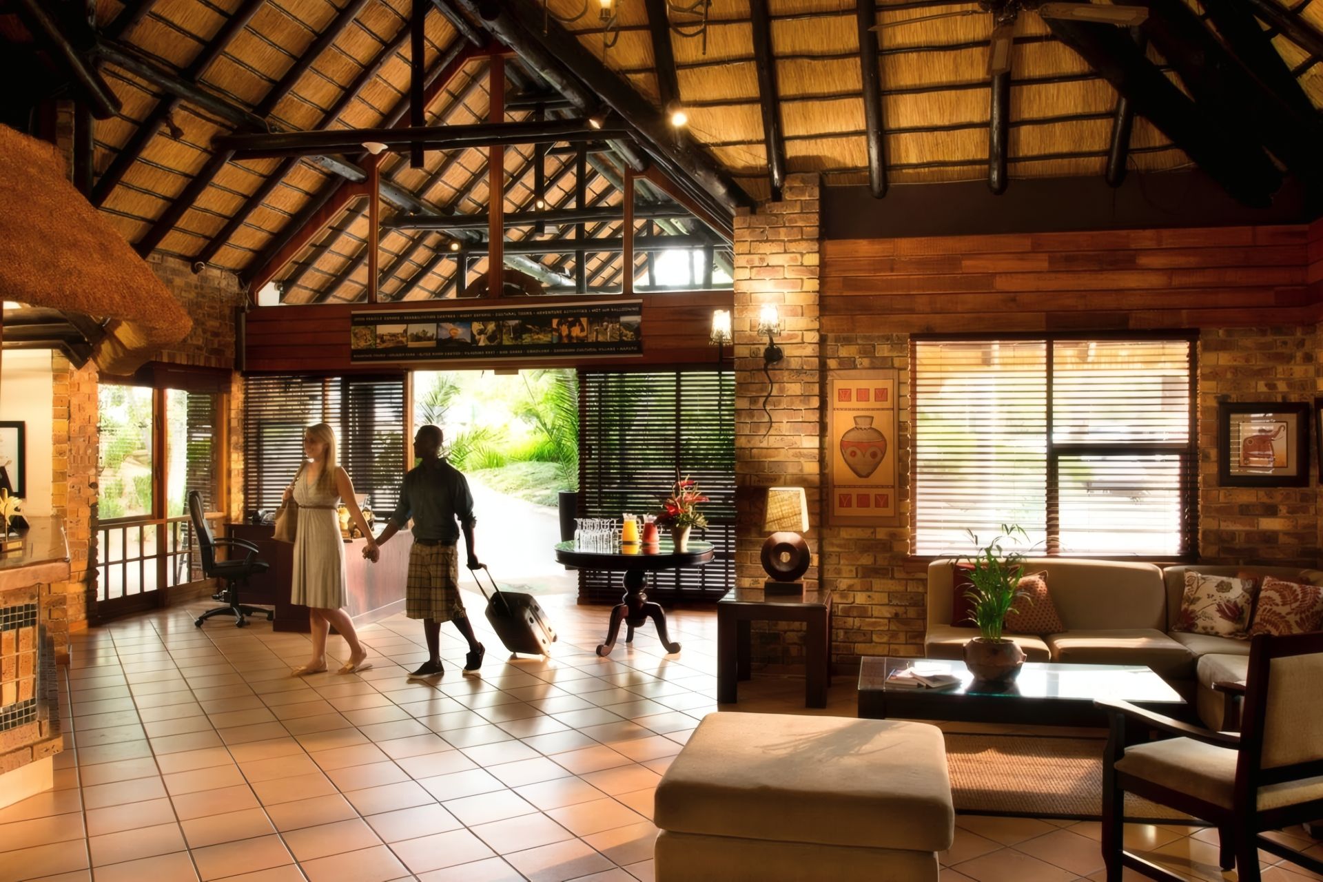 A spacious lobby with a high ceiling, a brick wall, and a large window.