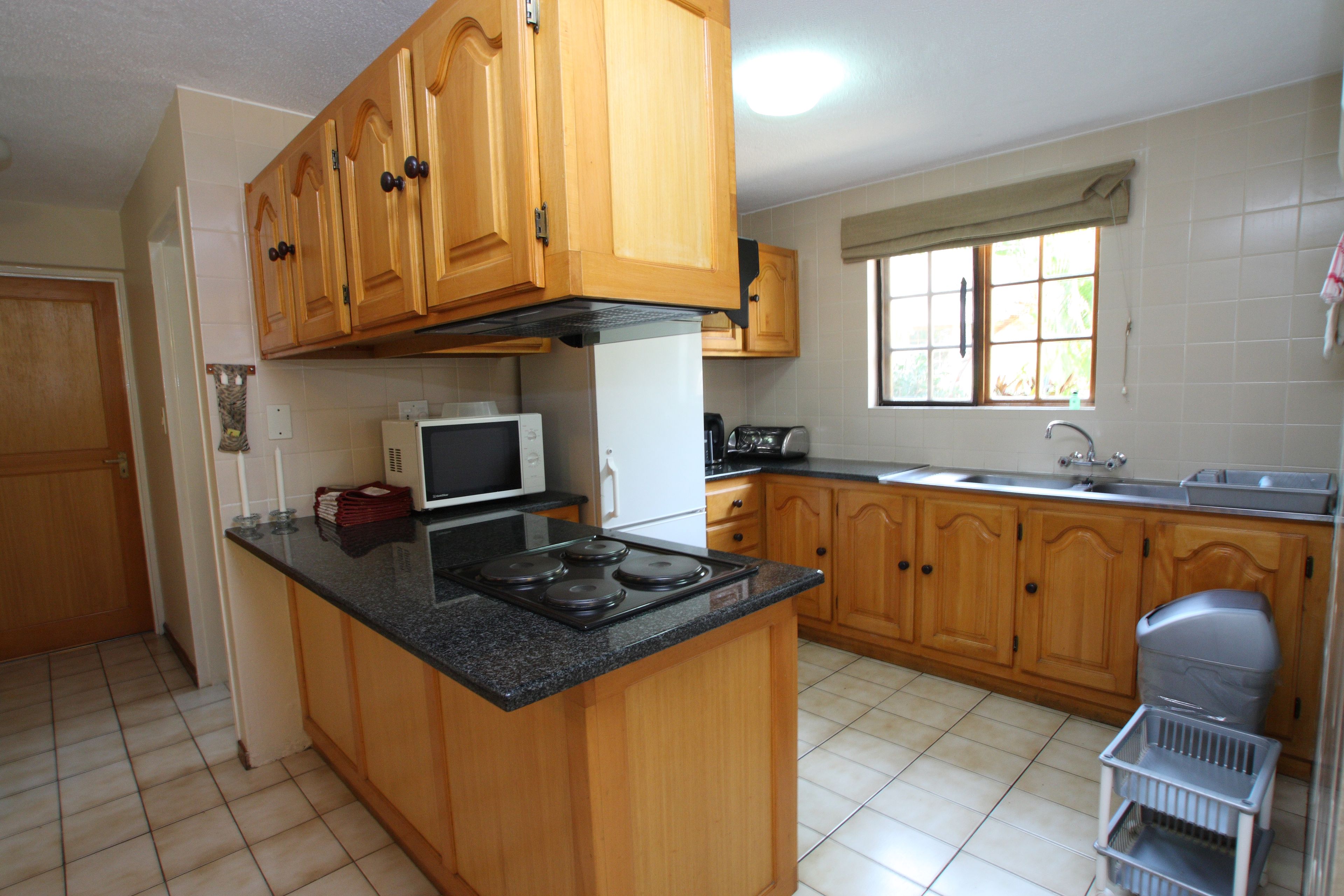 A kitchen with wooden cabinets, a stove, a microwave, and a window with a view.
