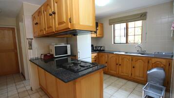 A kitchen with wooden cabinets, a stove, a microwave, and a window with a view.