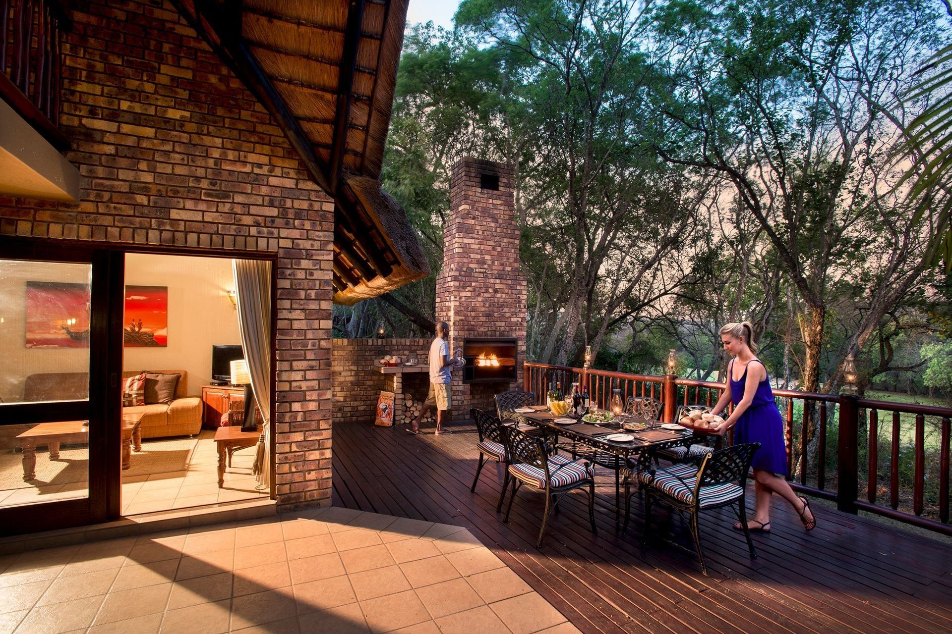 Una terraza con chimenea de ladrillo, mobiliario exterior y una mesa de comedor lista para una comida.