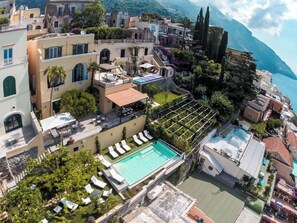 Un área de piscina en la azotea con sillones de descanso, una pérgola y vistas al mar.