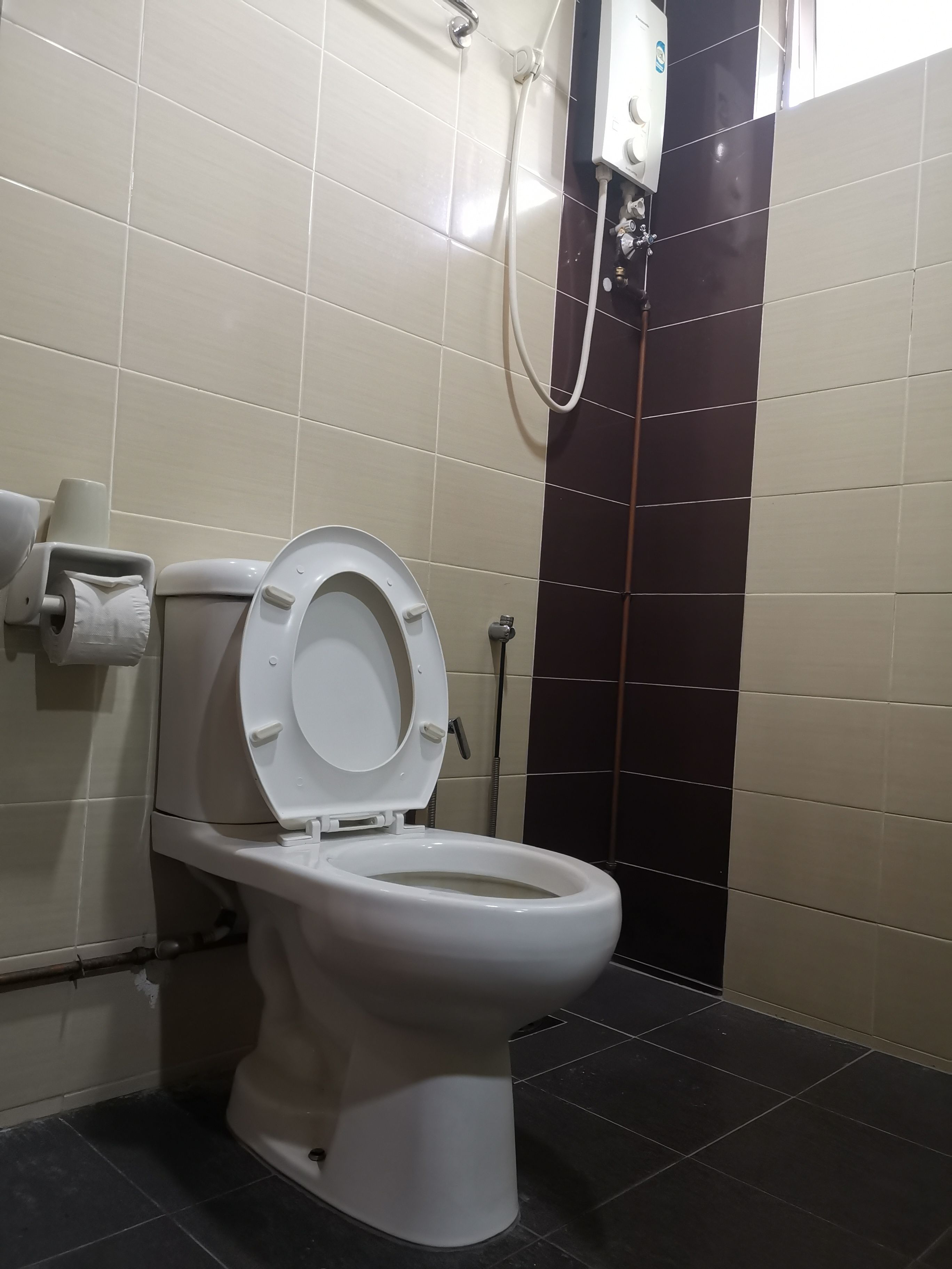 A toilet with a paper towel holder and a hand dryer.