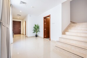 Un pasillo limpio y moderno con una escalera, una planta en maceta y puertas de madera.