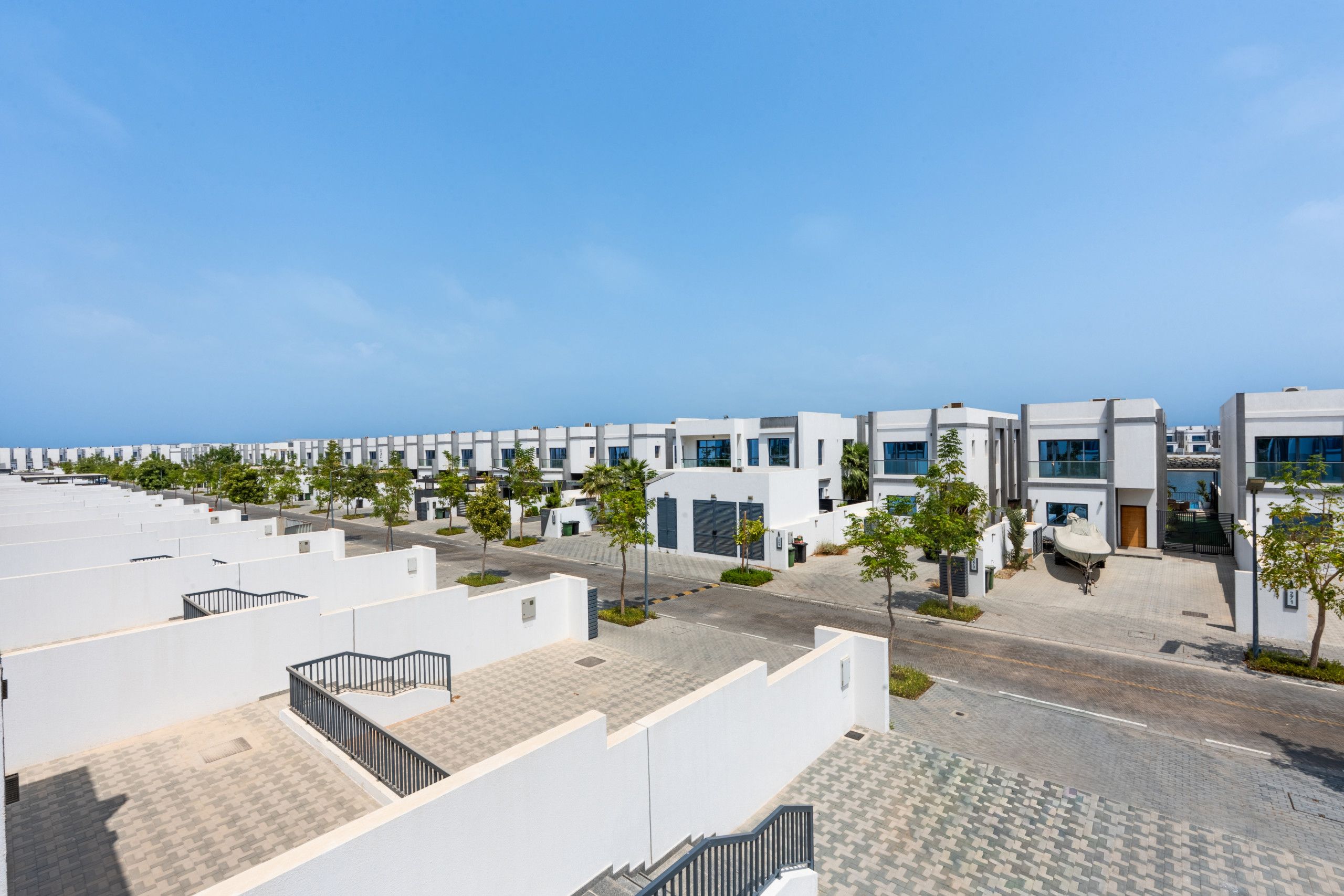 Un área residencial moderna con edificios blancos, calles pavimentadas y pequeños árboles.