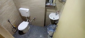 A small bathroom with a toilet, bidet, sink, and a storage cabinet. - Hotel Pratap (Etawah)