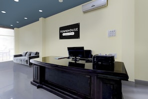 A reception desk with a computer, a sign indicating it's a company-serviced townhouse, and a window with a view. - Super Townhouse Cherlapally Bus Terminal (Hyderabad)