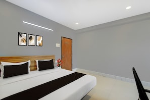 A hotel room with a bed, a wooden headboard, a wall-mounted light, and a door. - Super Townhouse Cherlapally Bus Terminal (Hyderabad)