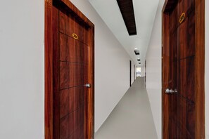 Corredor com portas de madeira identificadas com números, que leva a um quarto com vista.