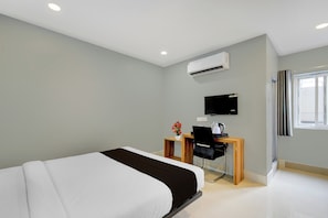 A modern hotel room with a bed, a desk with a chair, a television, and an air conditioning unit. - Super Townhouse Cherlapally Bus Terminal (Hyderabad)