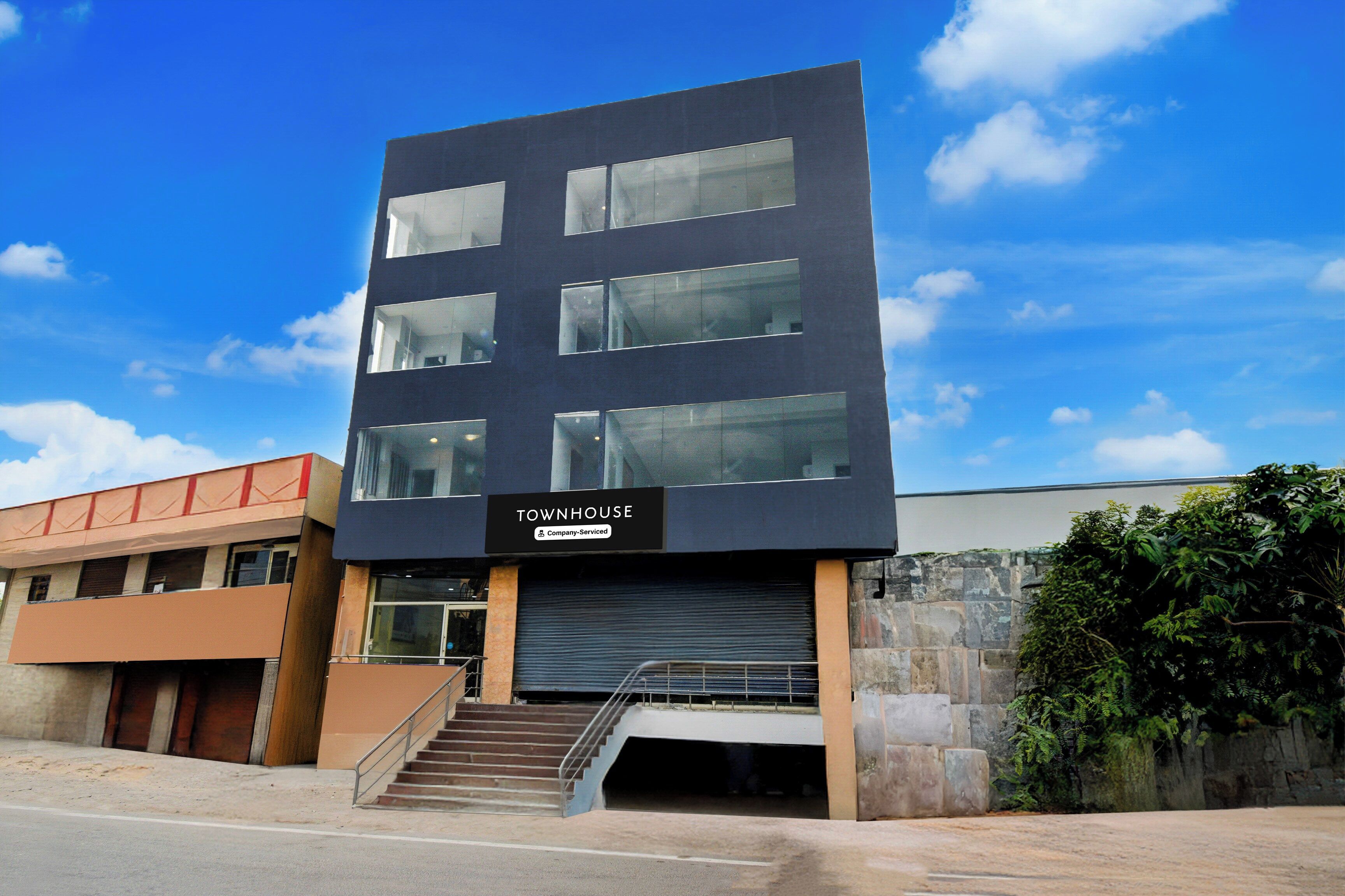 A modern building with a sign reading 'TOWNHOUSE' and a staircase leading to an entrance.