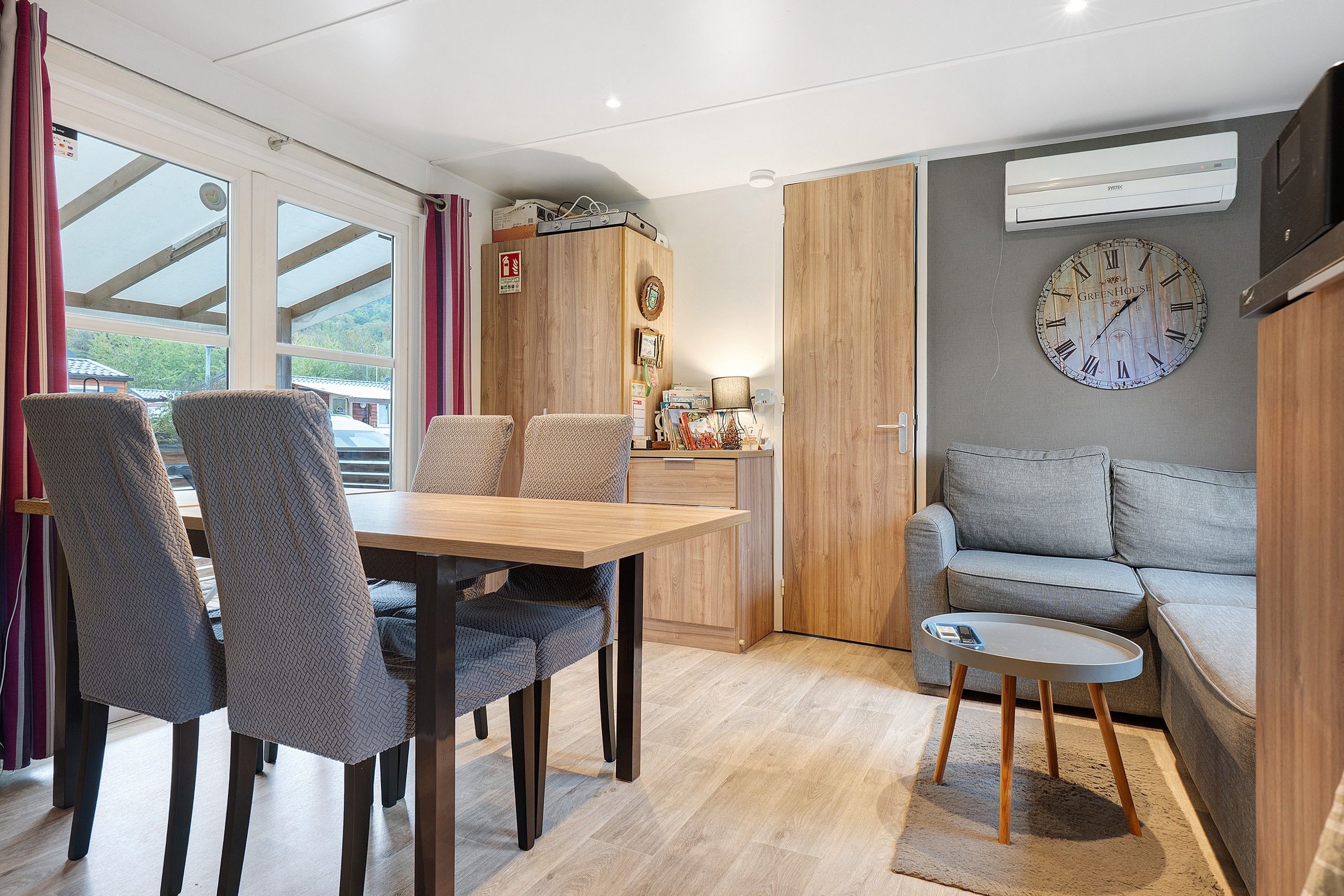 Un interior moderno con comedor, sofá y un reloj de pared.