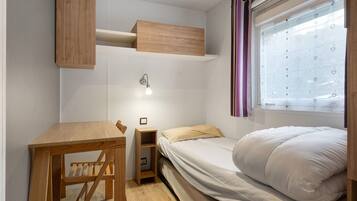 Un dormitorio compacto con una cama litera, un escritorio de madera pequeño y una mesita de noche.