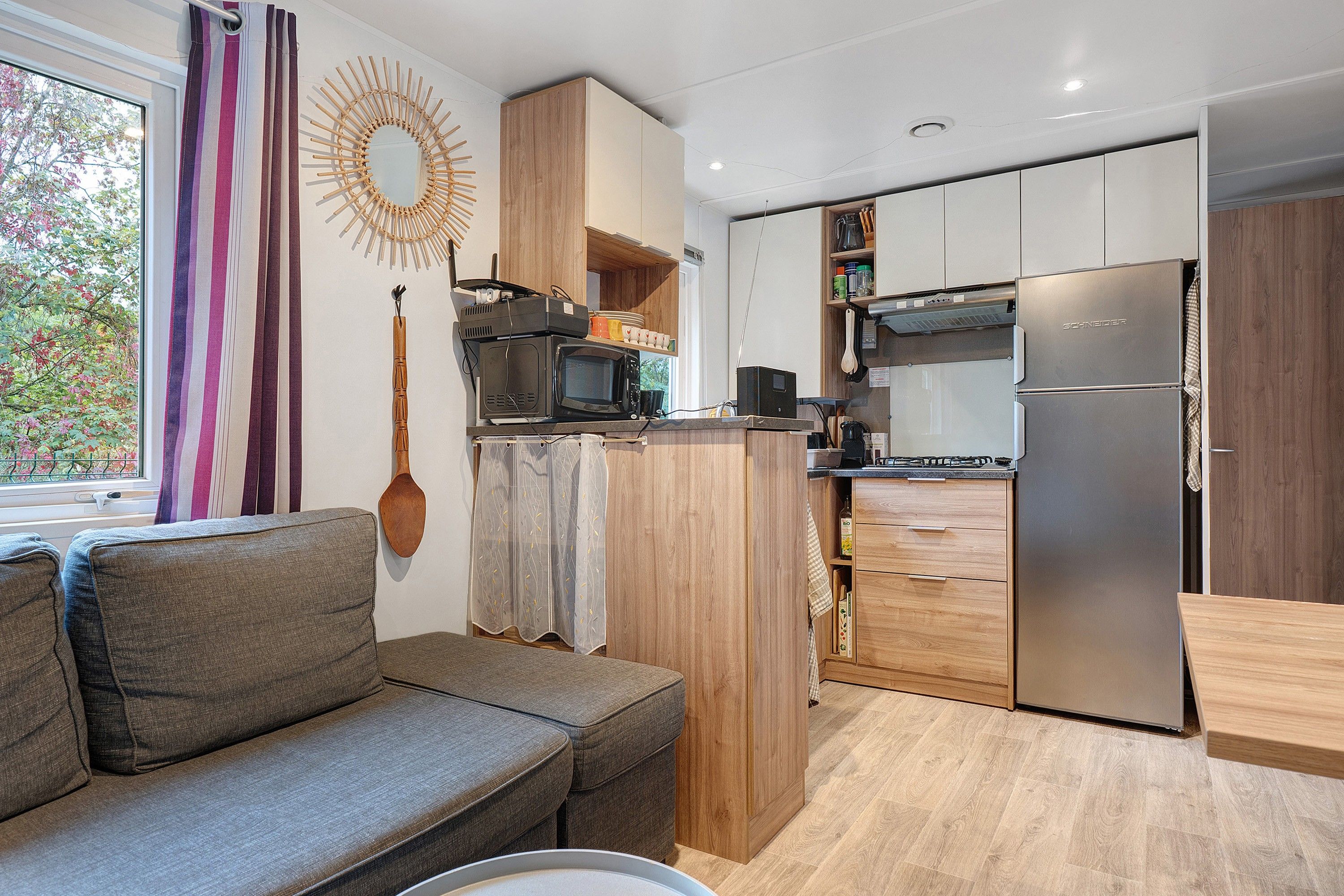 Una cocina compacta con microondas integrado, refrigerador y armarios de madera.