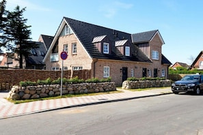 Ein zweigeschossiges Haus mit einer Stein-Fassade, einem schwarzen Dach und einem gepflasterten Auffahrt.