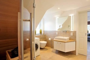 Ein modernes Badezimmer mit Waschmaschine, Toilette und einem großen Spiegel über dem Waschbecken.
