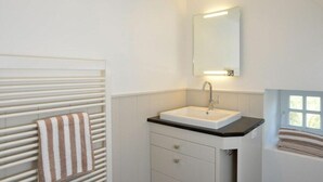 Une salle de bain avec un lavabo blanc, un porte-serviettes et une fenêtre.