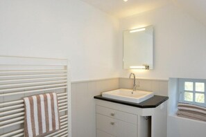 A bathroom with a white sink, a towel rack, and a window. - Witthüs 15 - stylish living under a thatched roof (Wenningstedt)
