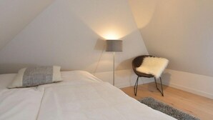 Une chambre à coucher avec un lit, une chaise, une lampe sur pied et un tapis.