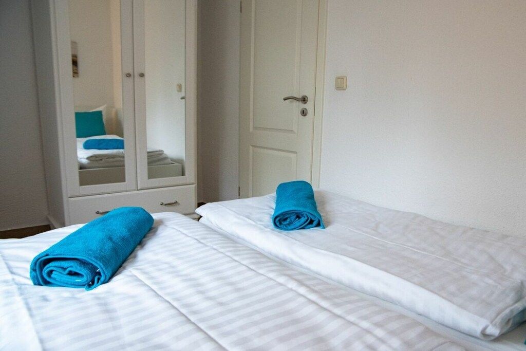 A hotel room with two beds, white bedding, and a wardrobe with a mirror.