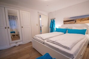 A bedroom with a bed, a wardrobe, and a painting on the wall. - Captain's House Apartment 2 (Cuxhaven-Duhnen)