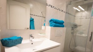 A bathroom with a white sink, a glass shower enclosure, and a blue towel. - Captain's House Apartment 2 (Cuxhaven-Duhnen)