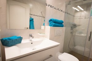 A bathroom with a white sink, a glass shower enclosure, and a blue towel. - Captain's House Apartment 2 (Cuxhaven-Duhnen)